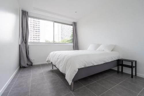une chambre blanche avec un lit et une fenêtre dans l'établissement Appartement 2 Chambres - Porte de Choisy, à Paris