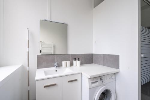 une salle de bain blanche avec une machine à laver et un lavabo dans l'établissement Appartement 2 Chambres - Porte de Choisy, à Paris