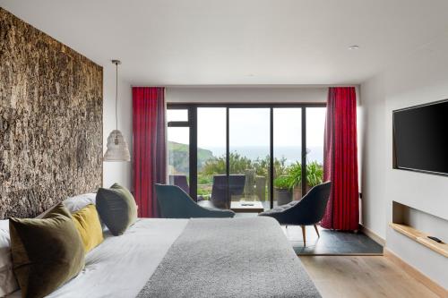 a bedroom with a large bed with chairs and a television at Bedruthan Hotel & Spa in Newquay