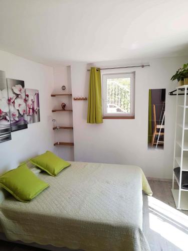 une chambre avec un lit avec des oreillers verts et une fenêtre dans l'établissement Mazet 2 pers dans havre de paix cévennol, à Laroque