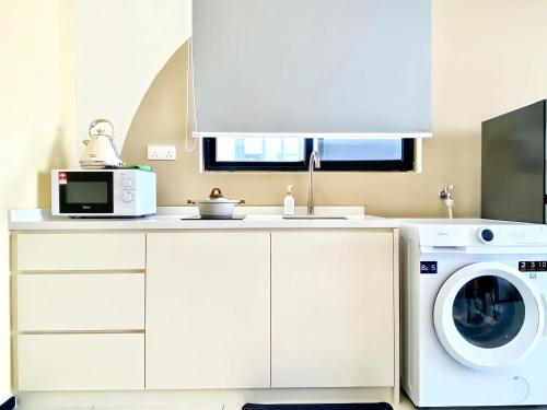 a kitchen with a washing machine and a microwave at Urban Suites George Town in Jelutong