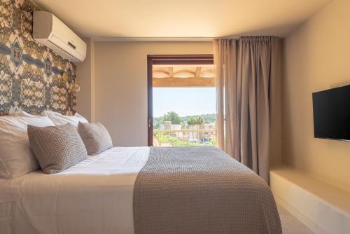 a bedroom with a large bed and a window at MalaQuita Hotel Boutique in Santa Eularia des Riu