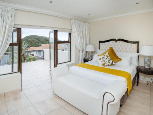 a white bedroom with a bed and a balcony at The Villa @ Balugha River Estate in Glengariff