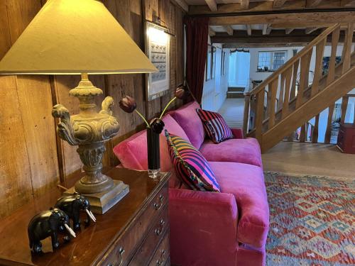 a living room with a pink couch and a lamp at Hewletts Mill in Castle Cary