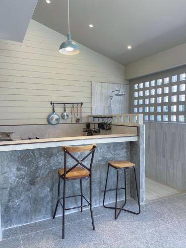 a kitchen with a counter and two stools in it at AobOun House Bangsaen บ้านโอบอุ่น บางแสน in Bangsaen