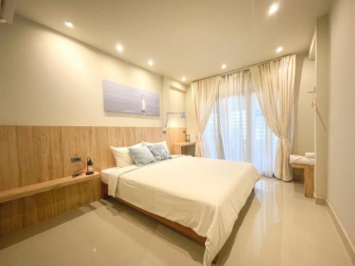 a bedroom with a large bed and a window at AobOun House Bangsaen บ้านโอบอุ่น บางแสน in Bangsaen