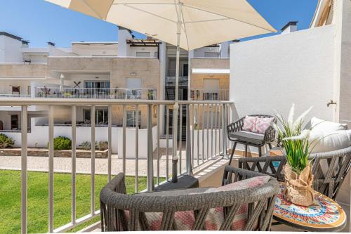 a balcony with two chairs and an umbrella at Apartment Andorinha-pretty Holiday Home With Pool in Santa Luzia