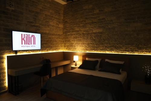 a bedroom with a bed and a tv on a brick wall at Kilim Boutique Hotel in Baku