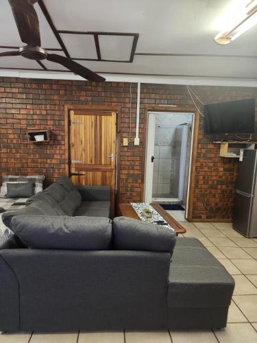 a living room with a couch and a brick wall at Cassiandra Place unit 2 in Richards Bay