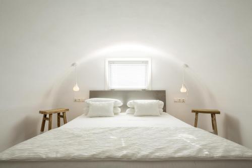a white bedroom with a large bed with two pillows at Art Hotel Santorini in Pirgos