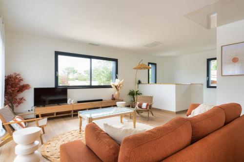 un salon avec un canapé et une table dans l'établissement Villa Sunset 1 prestigious heated swimming pool sea view for 8 people, à Lacanau-Océan