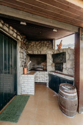 an outdoor kitchen with a stone wall and a barrel at HAGAH Alojamentos - Gerês in Vieira do Minho