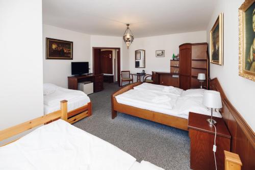 a bedroom with two beds and a desk and a television at Schlosshotel Marienbad in Mariánské Lázně