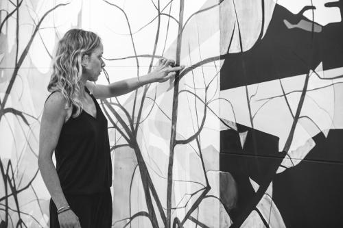 a woman in a black dress standing next to a wall at Art Hotel Santorini in Pirgos