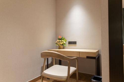 a desk with a chair and a vase of flowers at Copper Leaf Hotels, Tirunelveli in Tirunelveli