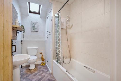 a bathroom with a sink and a toilet and a shower at The Gilpin Farmhouse, Lake District Getaway in Levens