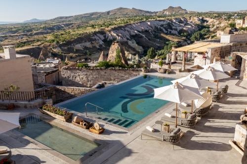 a pool with chairs and umbrellas at a resort at Argos in Cappadocia in Uchisar