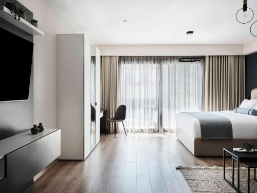 a bedroom with a bed and a desk and a tv at AVA Hotel & Residences Athens Riviera in Athens