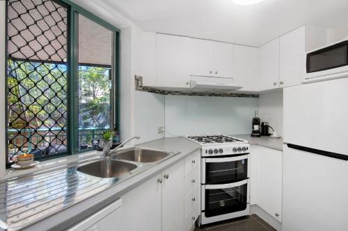 a white kitchen with a sink and a window at Pets Paradise - Top location with FREE parking in Gold Coast