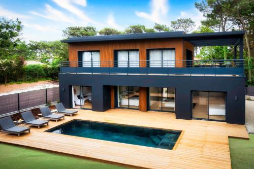 a house with a swimming pool in front of it at Villa Sunset 2 prestigious Balinese swimming pool sea view for 8 people in Lacanau-Océan