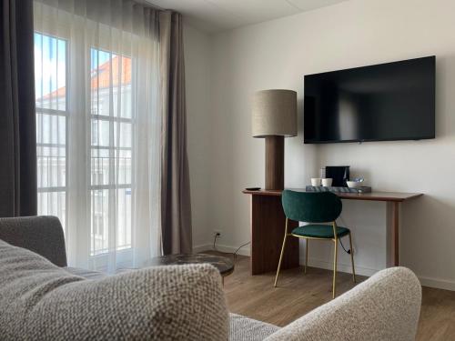 a living room with a couch and a tv and a chair at Best Western Hotel Herman Bang in Frederikshavn