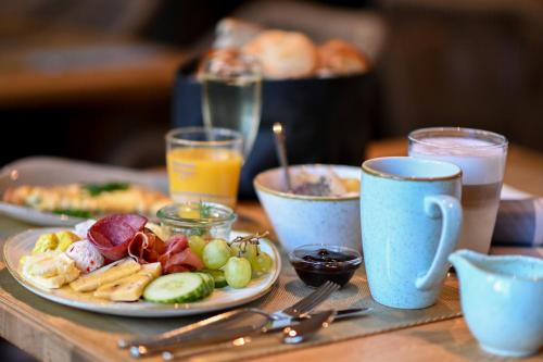 a table with a plate of food and glasses of milk at Vju Hotel Rügen in Göhren