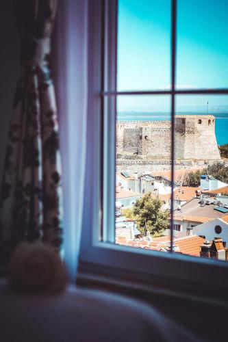 a window with a view of a city and a castle at Bozcaada Fresh Otel in Canakkale