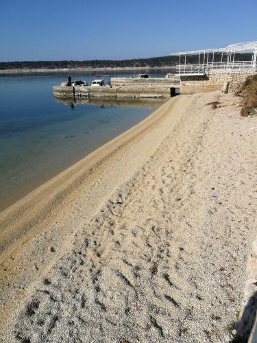 a sandy beach with footprints in the water at Apartmani Rukavina in Rab