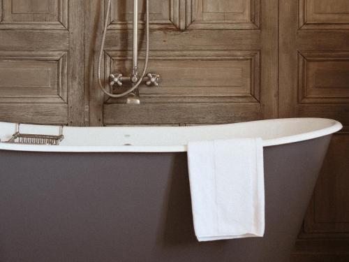 a bath tub with a towel hanging from it at Le Galinier Lourmarin, a Beaumier Guesthouse in Lourmarin