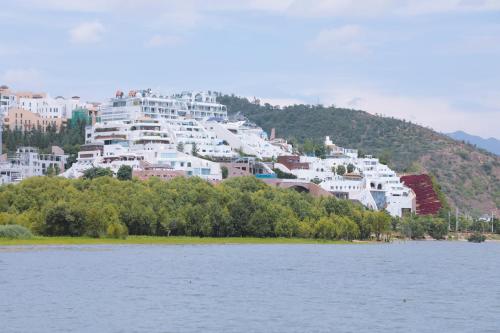 a group of white buildings on a hill next to a body of water at Dali Fish Inn Sea View Hotel in Dali
