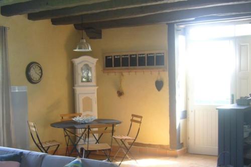 a dining room with a table and chairs and a clock at Maison d'hôtes les Escures in Acigné