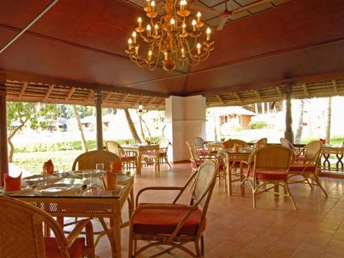 a restaurant with tables and chairs and a chandelier at Abad Harmonia Ayurvedic Beach Resort in Kovalam