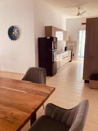 a living room with a wooden table and a kitchen at Ocean Whisper- psst! hidden gem in Kaipamangalam