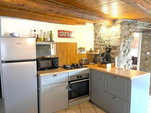 La cuisine est équipée d'un réfrigérateur blanc et d'un four micro-ondes. dans l'établissement Maison chaleureuse et rustique, à Annonay