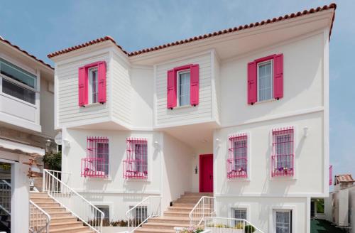 a white house with red shutters and stairs at Bozcaada Fresh Otel in Canakkale