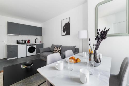 Il comprend une cuisine blanche et un salon avec une table blanche. dans l'établissement 2 pieces refait neuf metro Jaures - paris 19 - 4P - FLAT-GUEST, à Paris