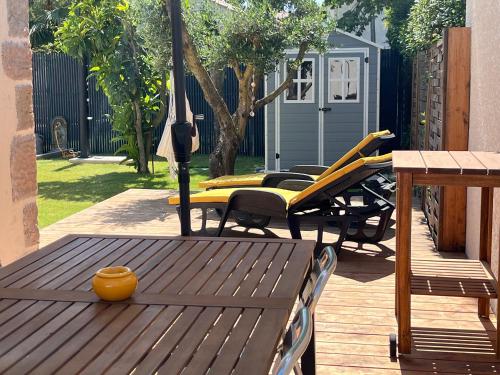 une terrasse avec des chaises, des tables et un parasol dans l'établissement Petite maison individuelle proche plage, à Mèze