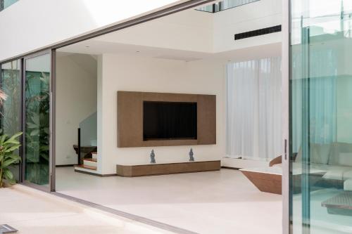 a living room with a tv and glass walls at Sun Diego Resort Pool Villa in Jomtien Beach