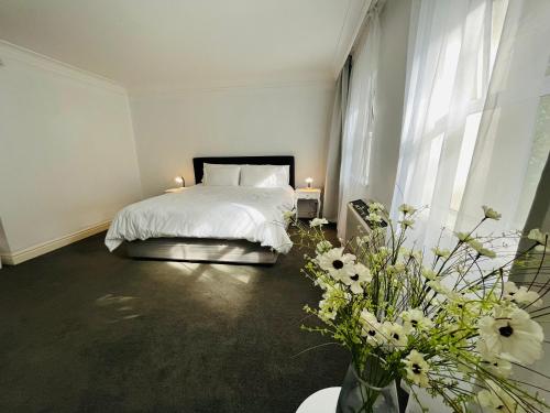 a bedroom with a bed with white sheets and flowers at Near CTICC Professional & Cosy Hotel Room in Cape Town