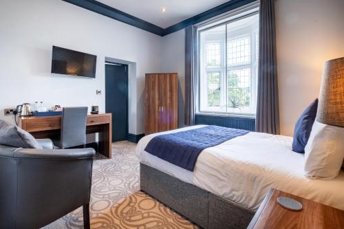 a hotel room with a bed and a desk at The Coach House Suffolk in Lowestoft