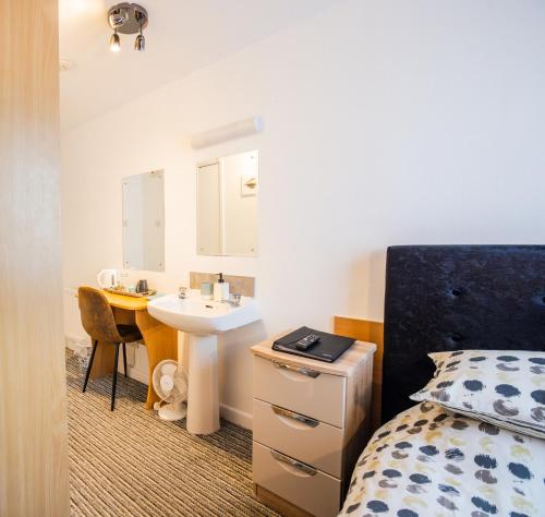 a bedroom with a bed and a sink and a desk at St Georges Guest House in St Peter Port