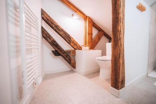 une salle de bain avec toilettes blanches et poutres en bois dans l'établissement Le Berry Cosy - Le Véritable Cocon - Proche Gare, à Châteauroux