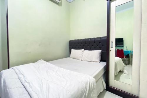 a bedroom with a mirror next to a bed at Wisma Falira Serang Syariah Mitra RedDoorz in Banjar