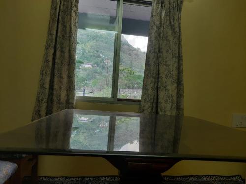 a glass table in front of a window at RAHUL Homestay in Sainj