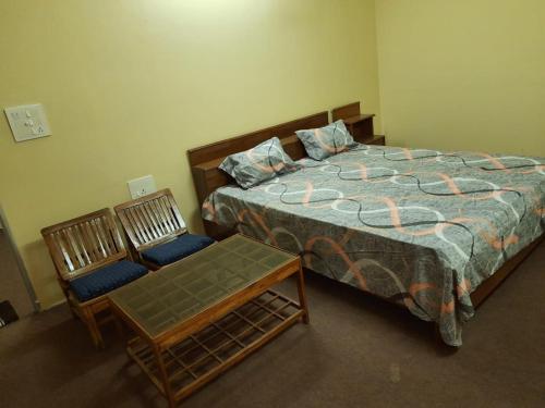 a bedroom with a bed and a pair of chairs at RAHUL Homestay in Sainj