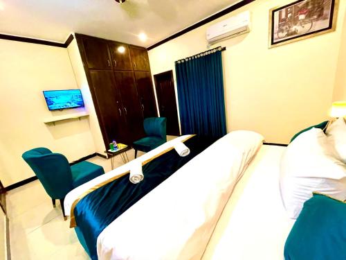 a hotel room with a bed and two chairs at Go Guest House Lhr in Lahore