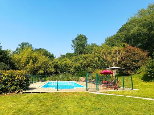 une piscine avec une table et un parasol dans l'établissement Gîte du Nouveau Monde, à Langoëlan