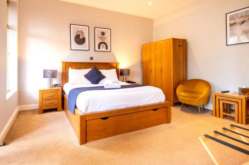 a bedroom with a bed and a yellow chair at The Coach House Suffolk in Lowestoft
