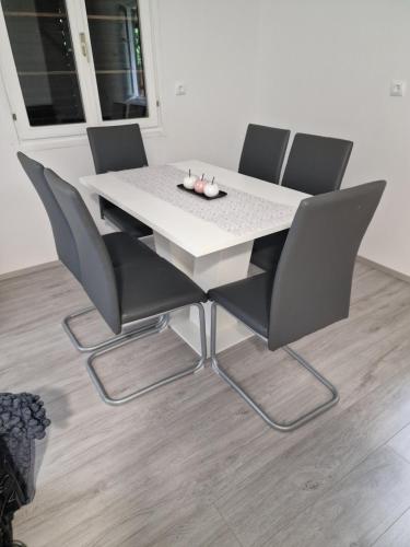 a white table with four chairs and a white table at Hiška 111 s kopalnimi kartami in Brežice
