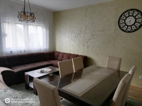a living room with a couch and a table and a clock at Apartman SATO in Brčko